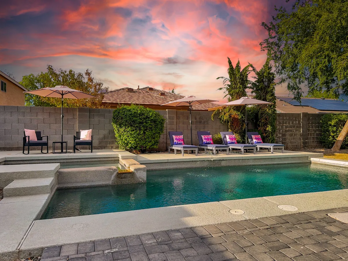 A serene outdoor view of the swimming pool, plush lounge chairs, sun umbrellas, and lush landscaping. The tranquil surroundings create a soothing atmosphere ideal for sunbathing or evening gatherings with friends and family.