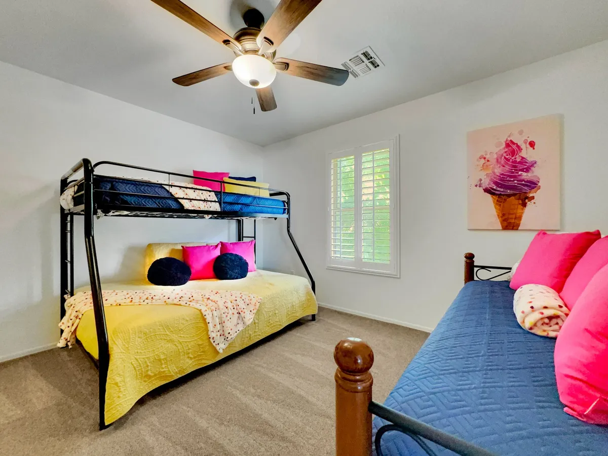 A playful and comfortable bunk room featuring a bunk bed with colorful throw pillows and wall art, ideal for children or group stays. The space invites both rest and playful activities.