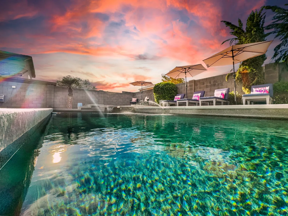 A striking exterior scene showcasing a sparkling swimming pool surrounded by umbrellas and lounge chairs, with a beautiful sky backdrop and a hint of a water fountain. The setup evokes a high-end resort feel, inviting relaxation and connection.
